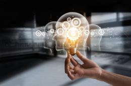 A hand holding a light bulb in form of a human head